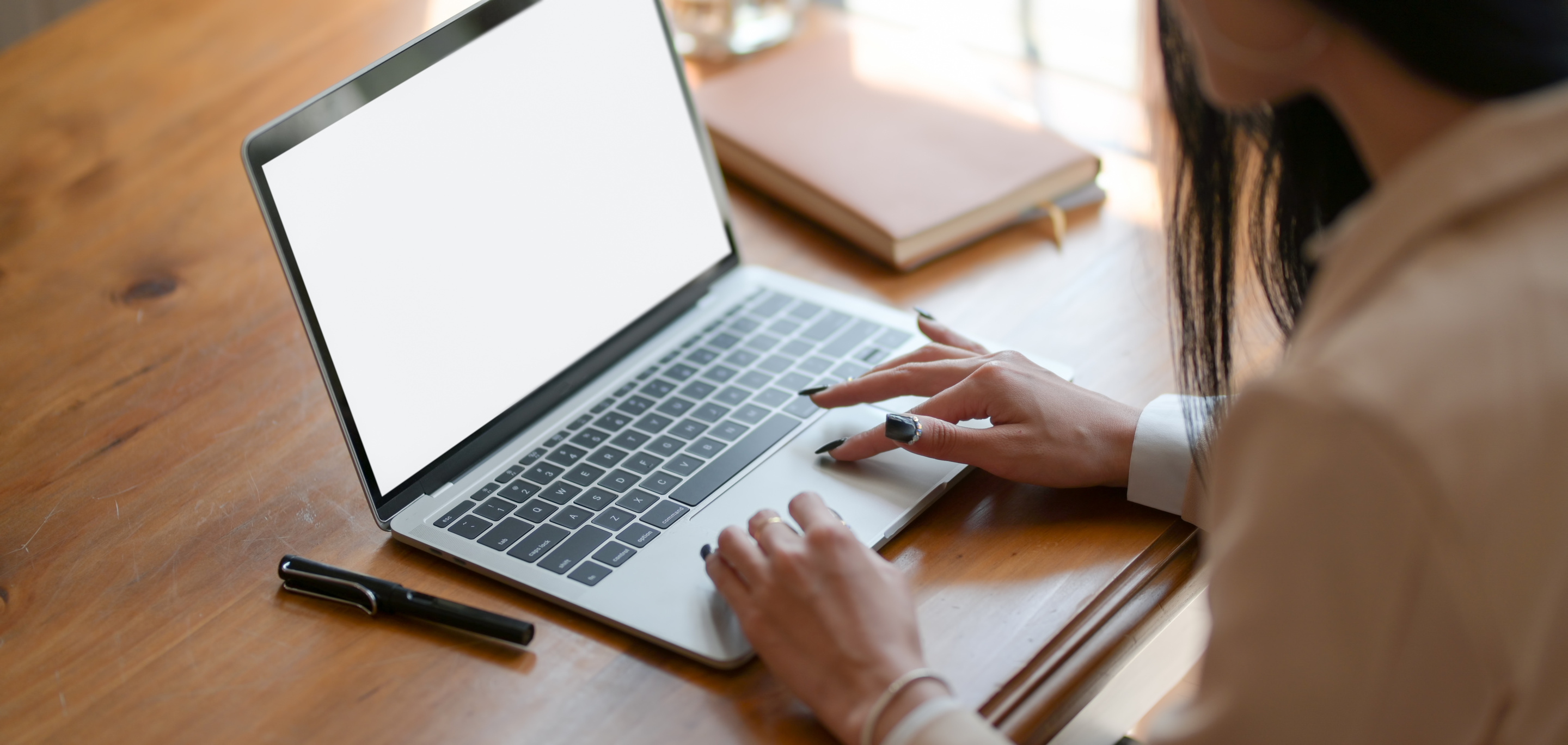 Person Using Macbook Air on Brown Wooden Table